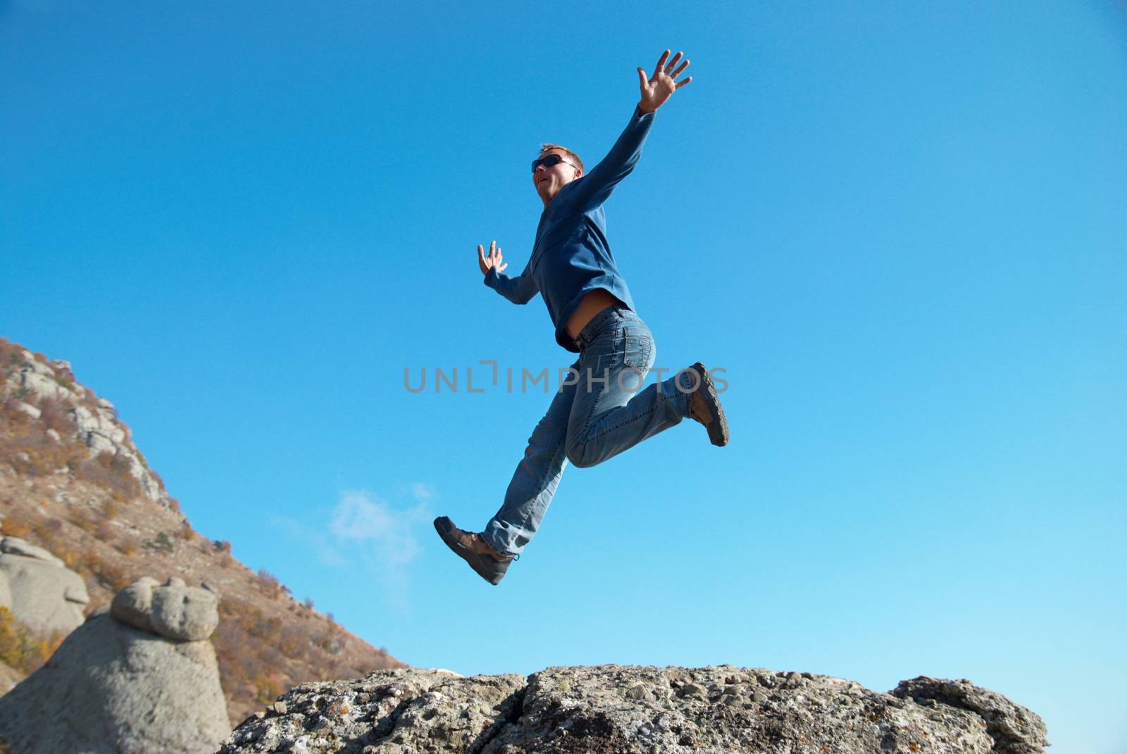 Man jumping on the rocks with landscape background