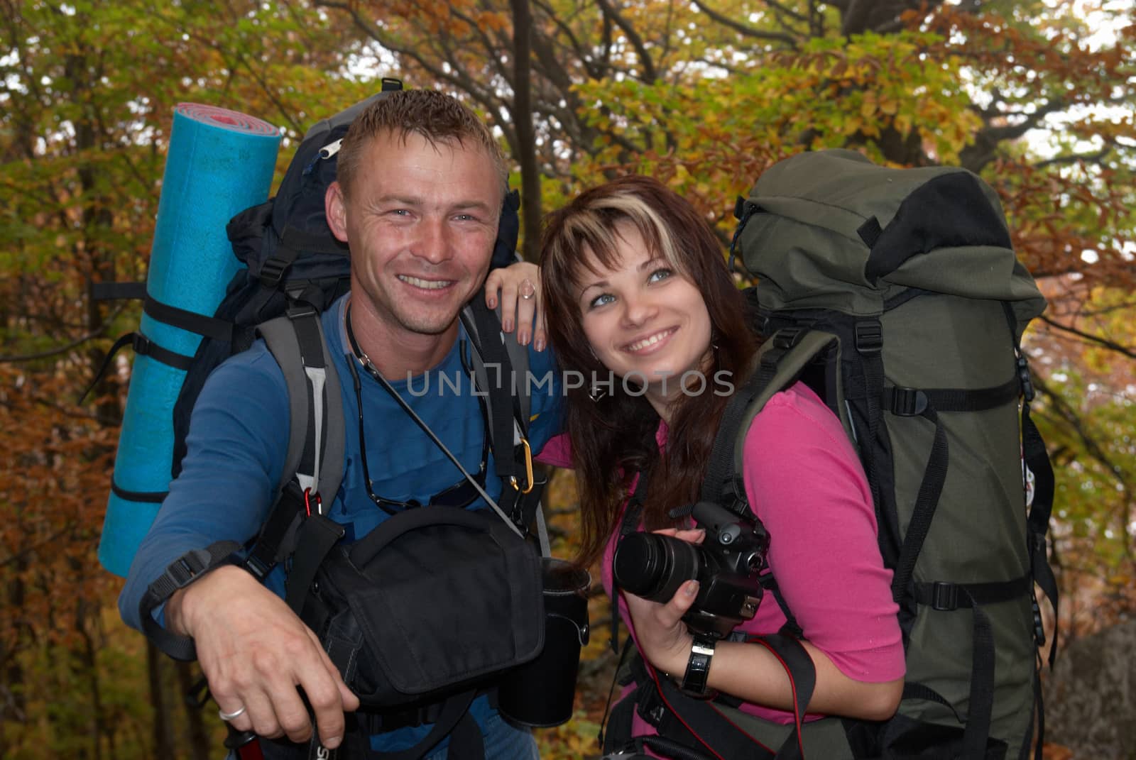 Young tourist couple in the autumn park with rucksacks