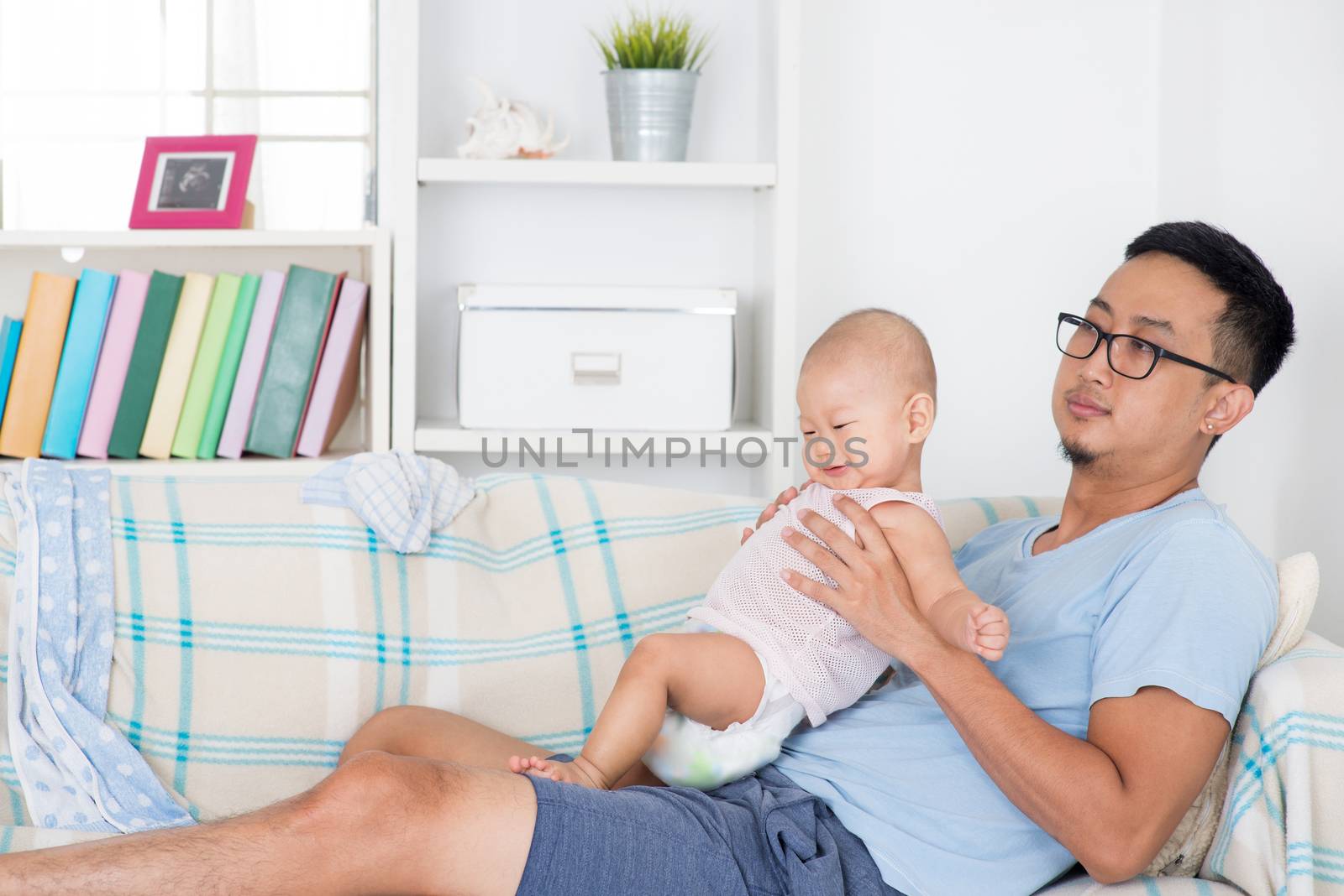 Exhausted father taking care baby alone at home. Asian family lifestyle at home.