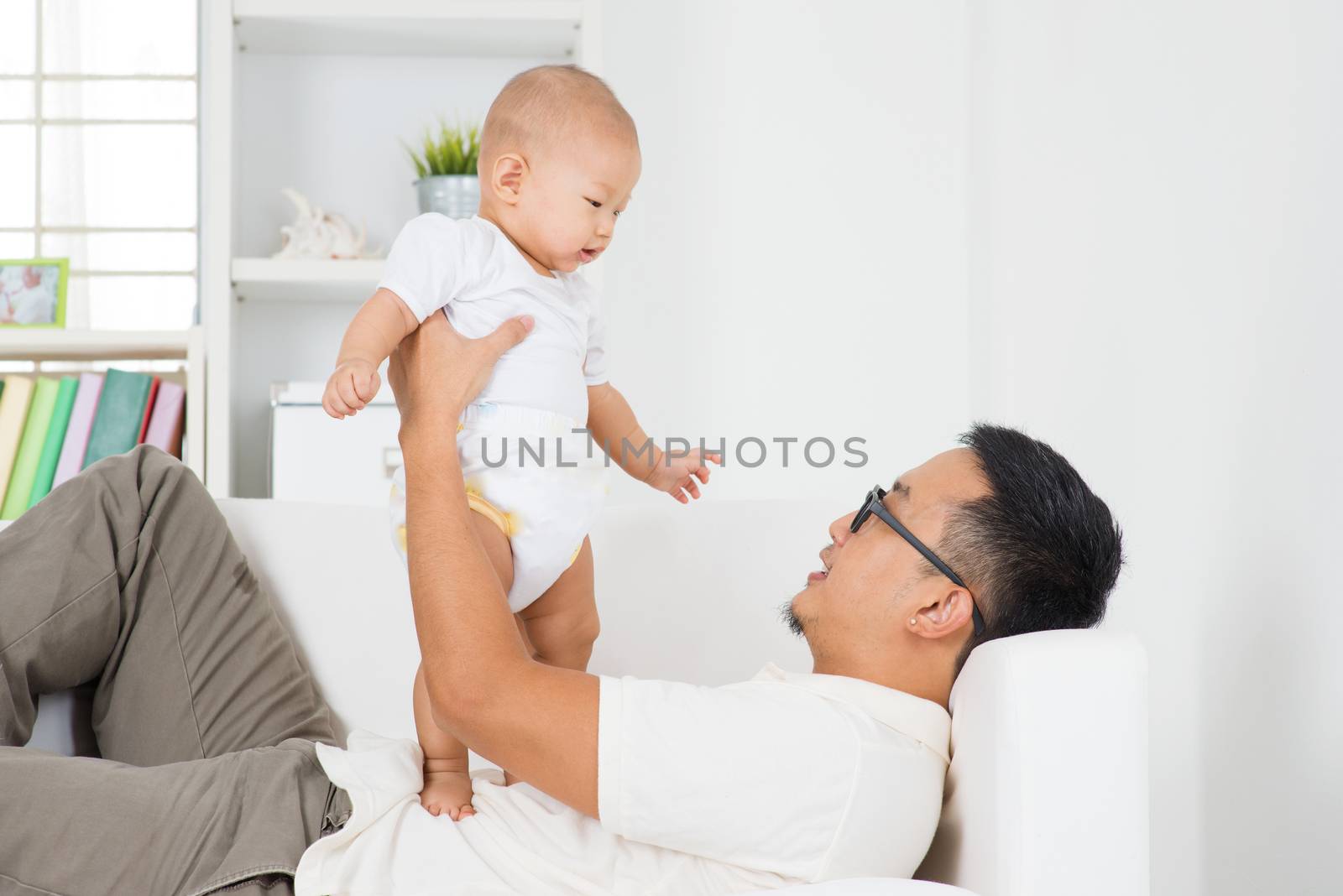 Asian family lifestyle at home. Father playing with baby boy indoors.