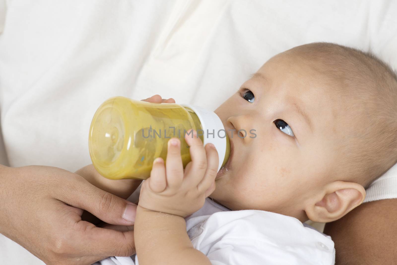 Father bottle feed solid food fruit puree to baby boy, Asian family lifestyle at home.