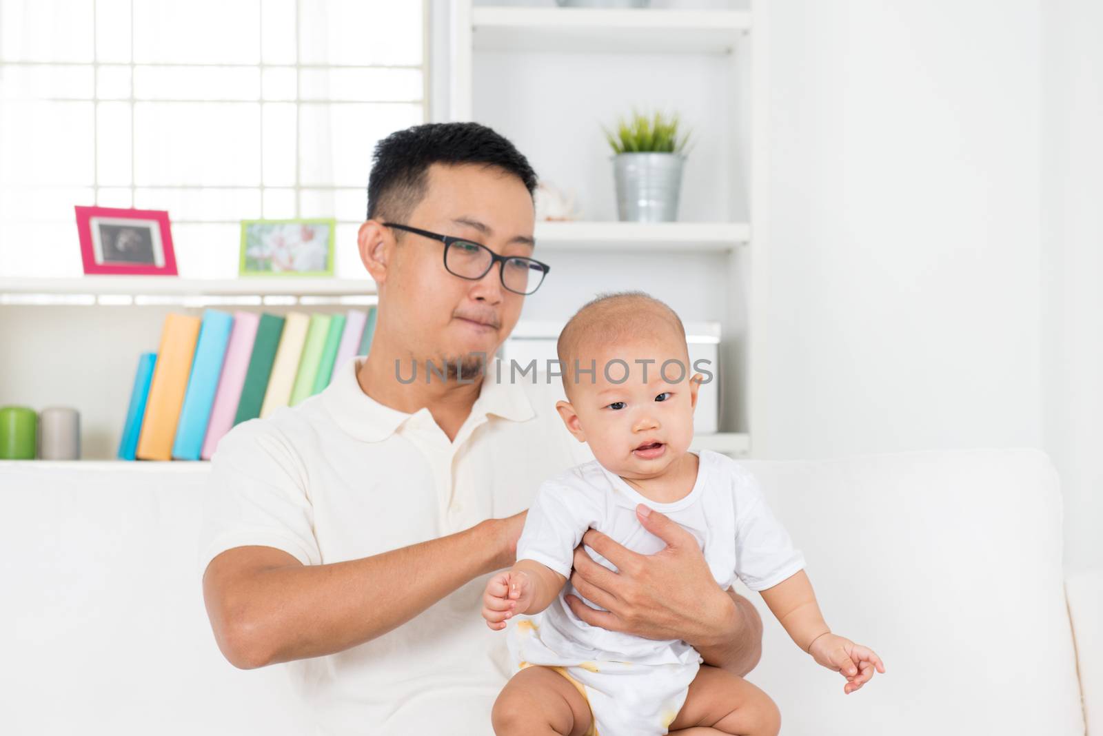 Father burping baby boy after meal, Asian family lifestyle at home.