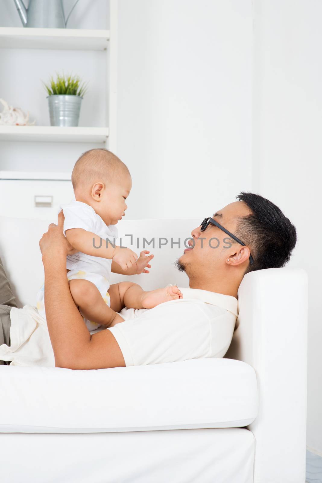 Father playing with baby boy indoors. Asian family lifestyle at home.