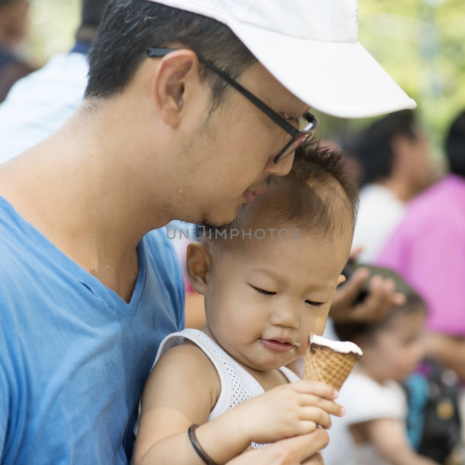 Father and child are eating ice creams on summer holidays. Candid family photo.