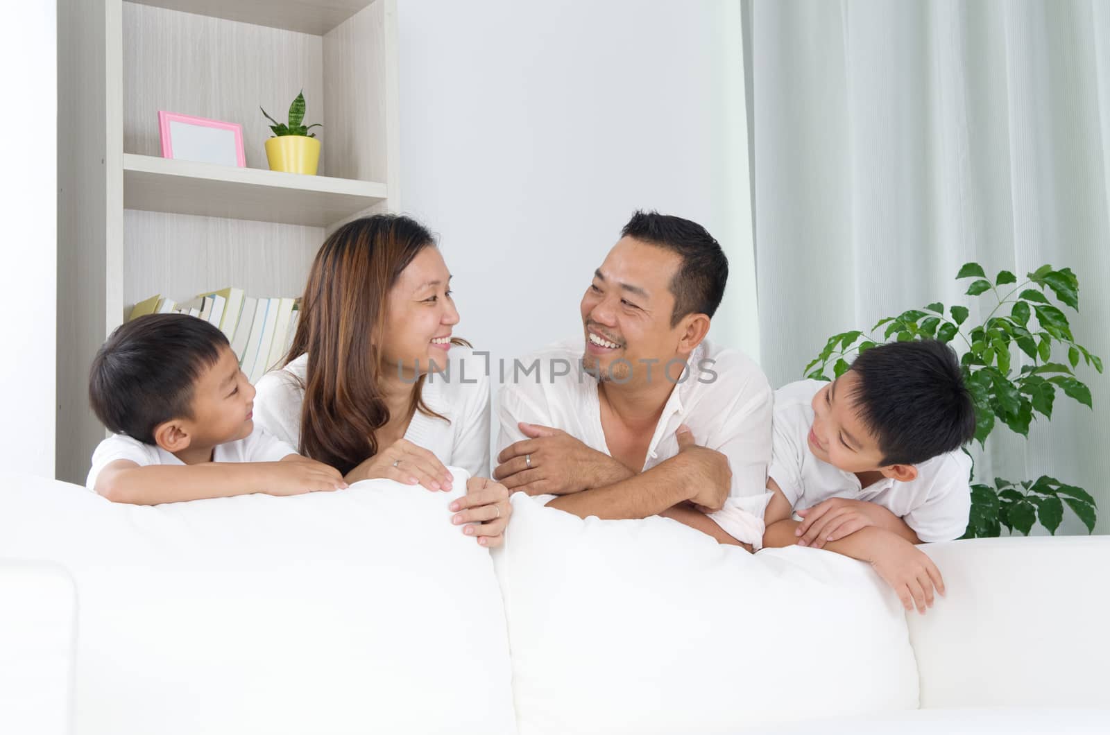 Asian family posing behind sofa.