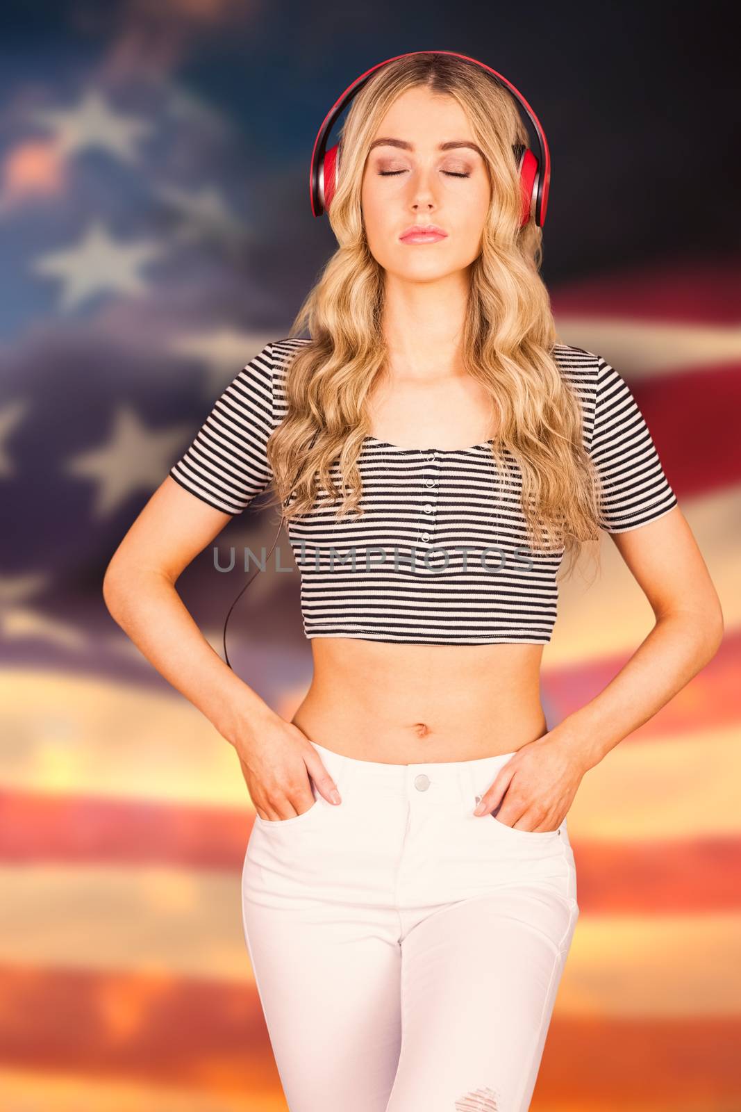Pretty young woman with headphones  against digitally generated american flag rippling over grass
