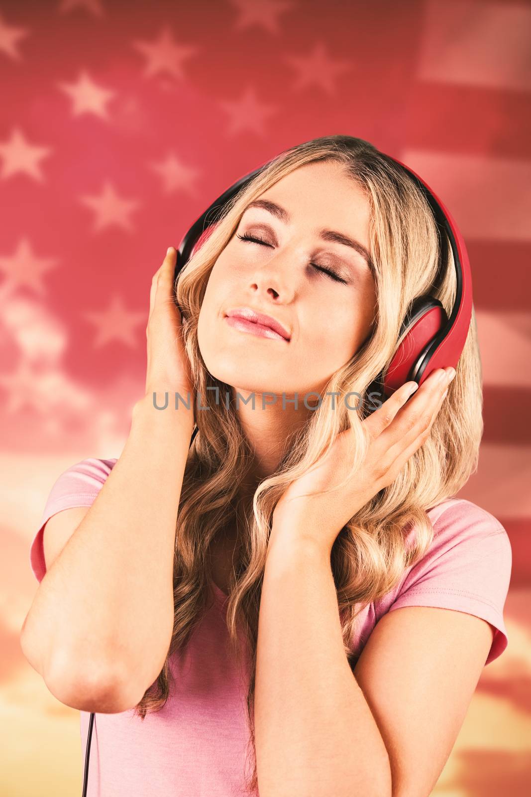 Pretty young woman with headphones  against american flag rippling against sunrise over mountains