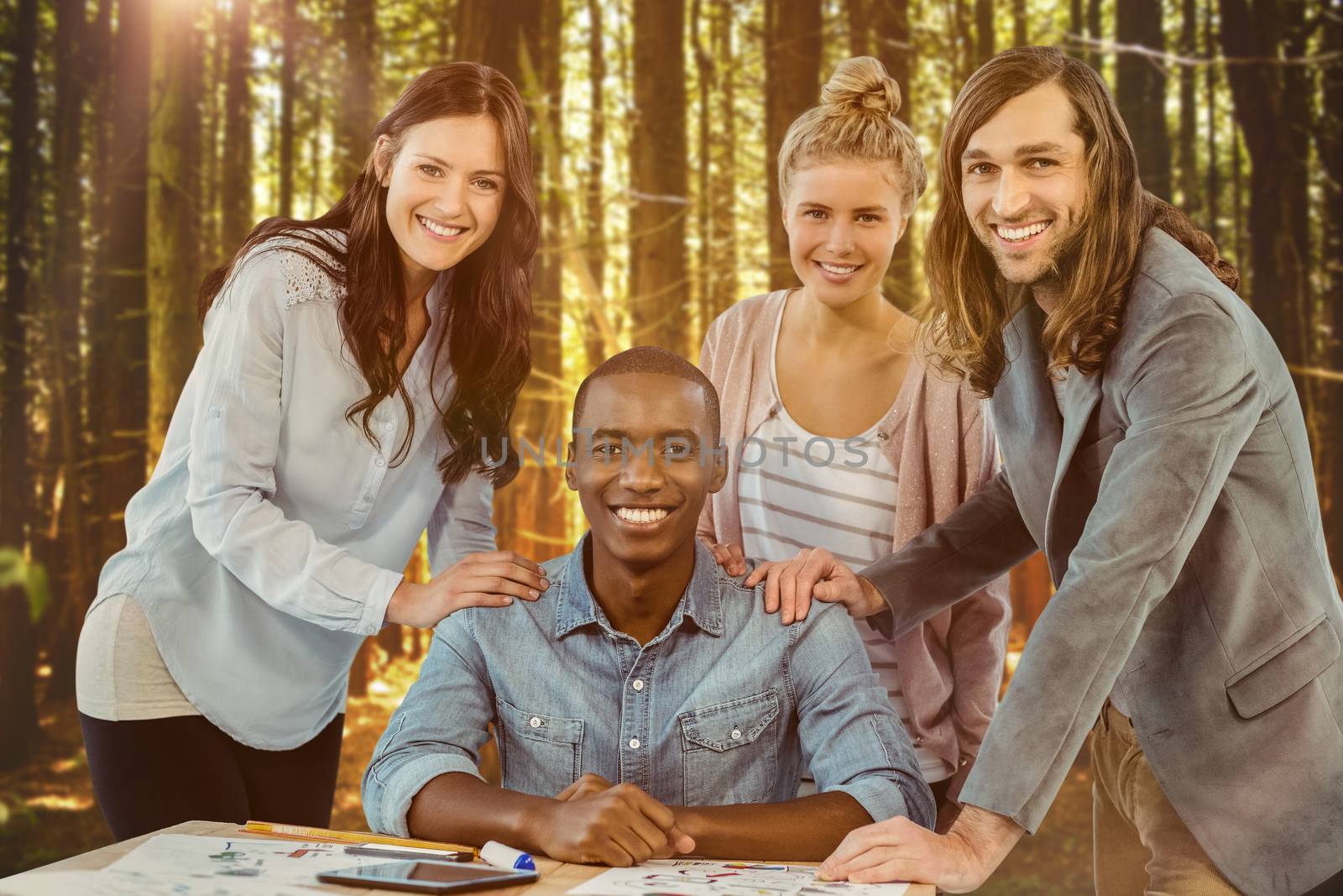 Portrait of smiling business team putting hands on man shoulder at desk  against trees in a woods