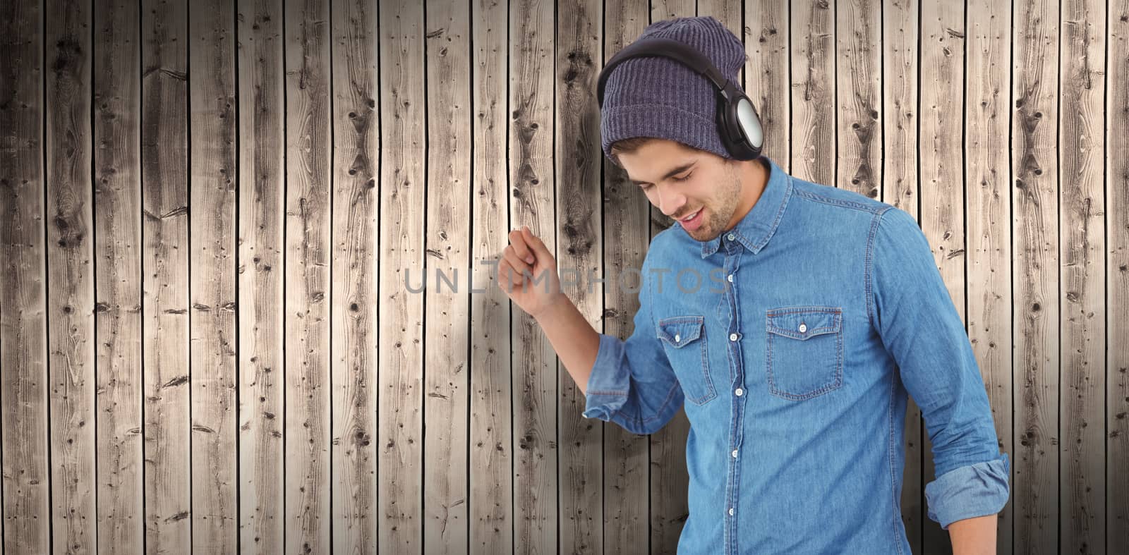 Hipster wearing headphones enjoying music against wooden planks background