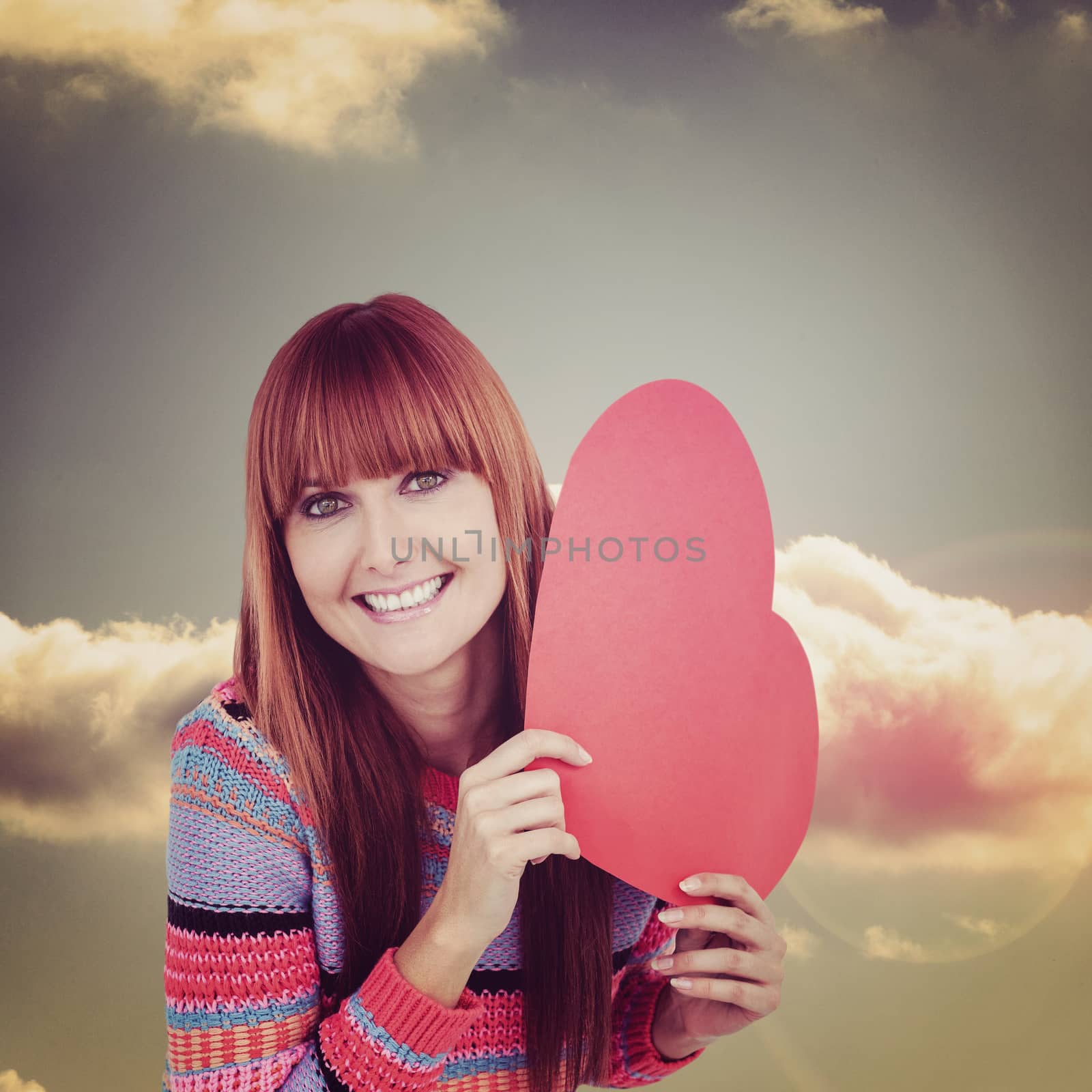 Smiling hipster woman holding a red heart against bright blue sky with cloud