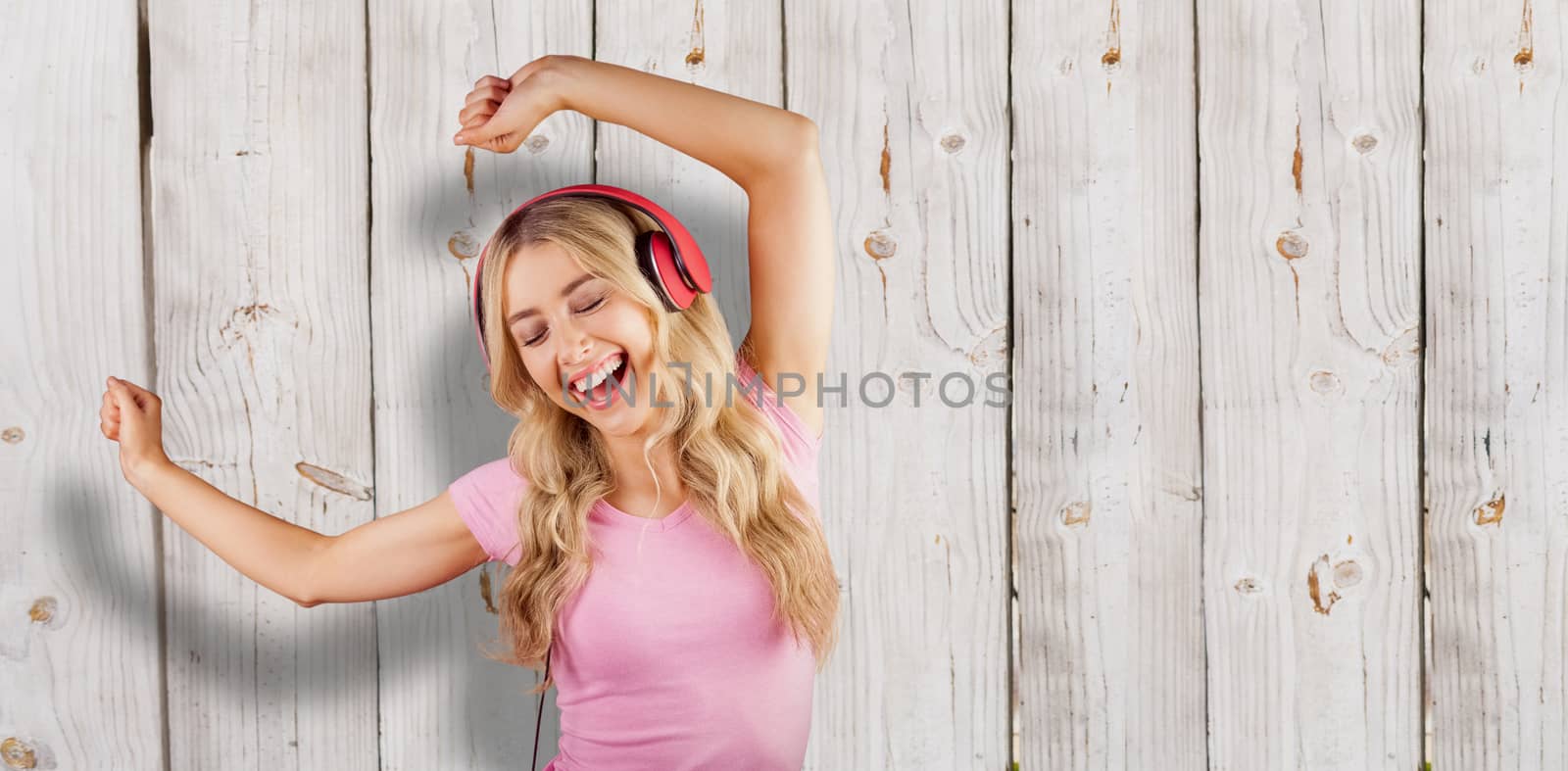 Beautiful woman dancing with headphones against wooden background