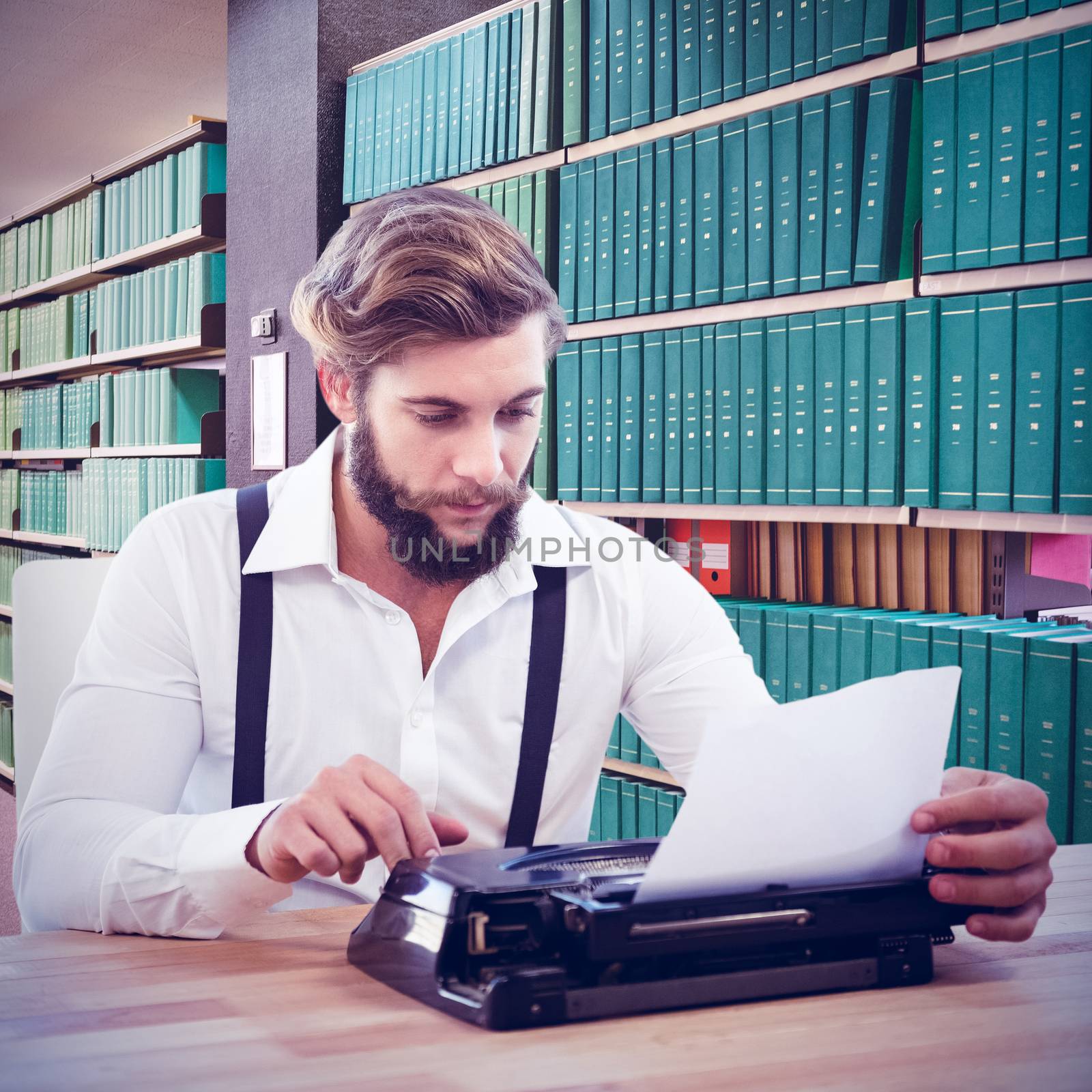 Hipster using typewriter at desk in office against close up of a bookshelf