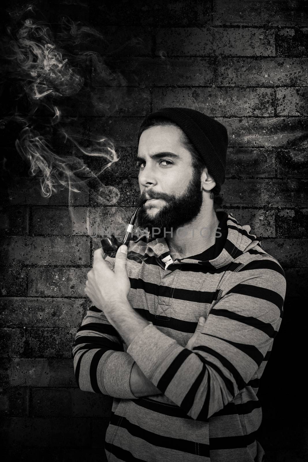 Portrait of serious hipster smoking pipe against texture of bricks wall