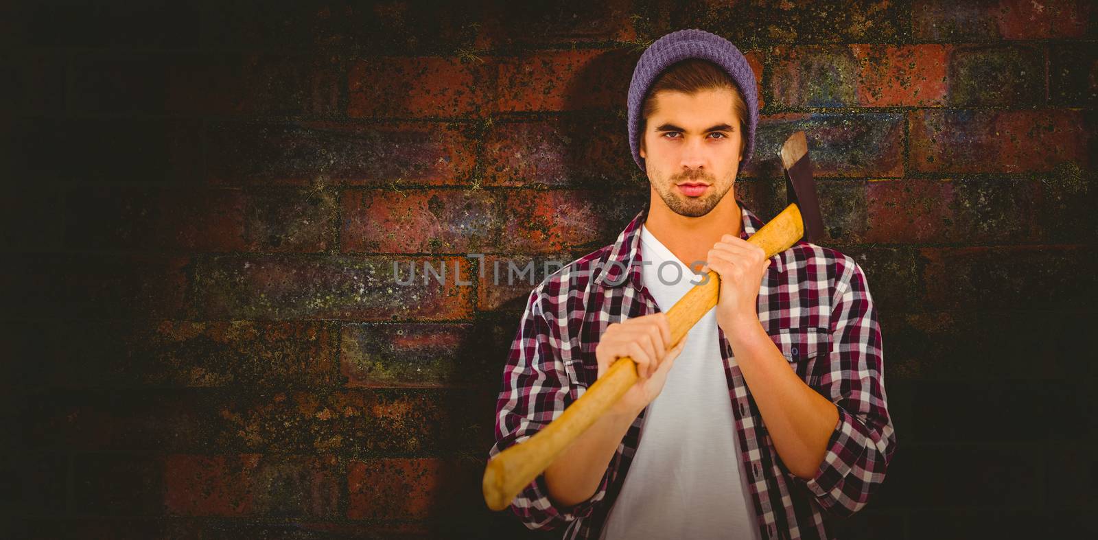 Portrait of confident man holding axe on shoulder against texture of bricks wall