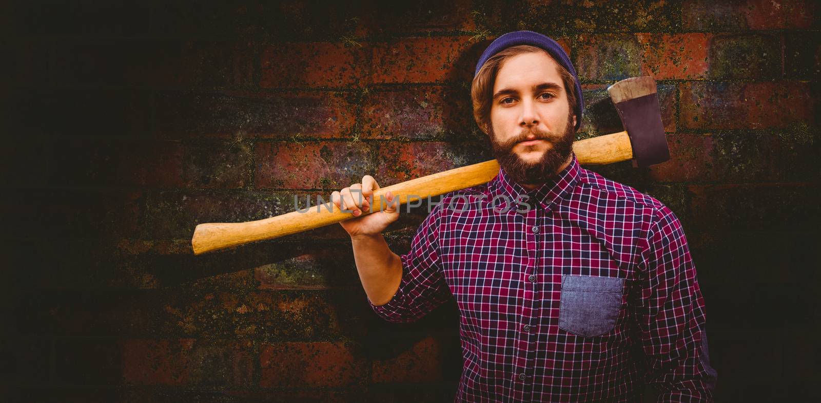 Hipster holding axe on shoulder against texture of bricks wall