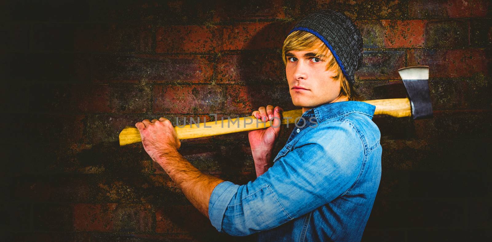 Profile of hipster standing with axe against texture of bricks wall