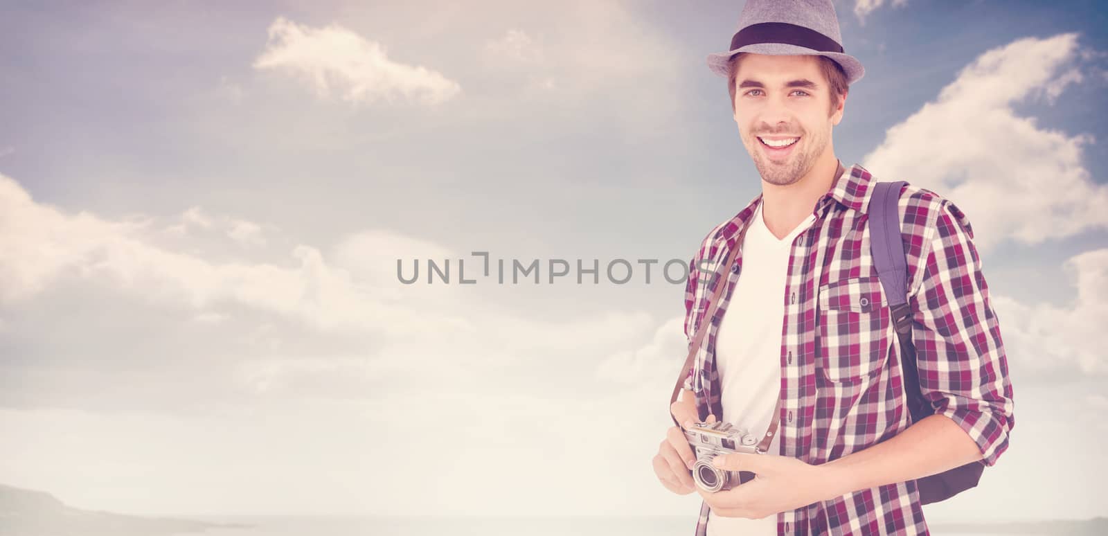Portrait of man smiling while holding camera against beach