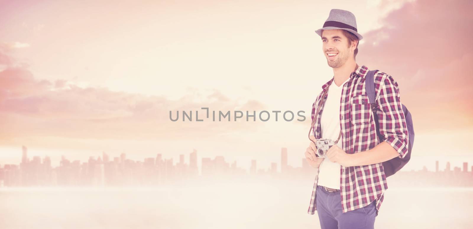 Happy man holding camera against cityscape on the horizon