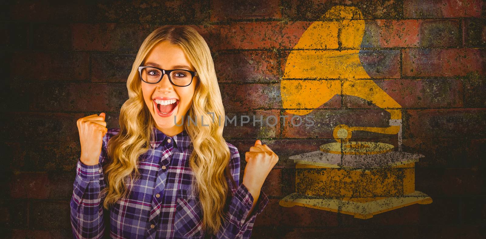 Gorgeous blonde hipster celebrating success against texture of bricks wall