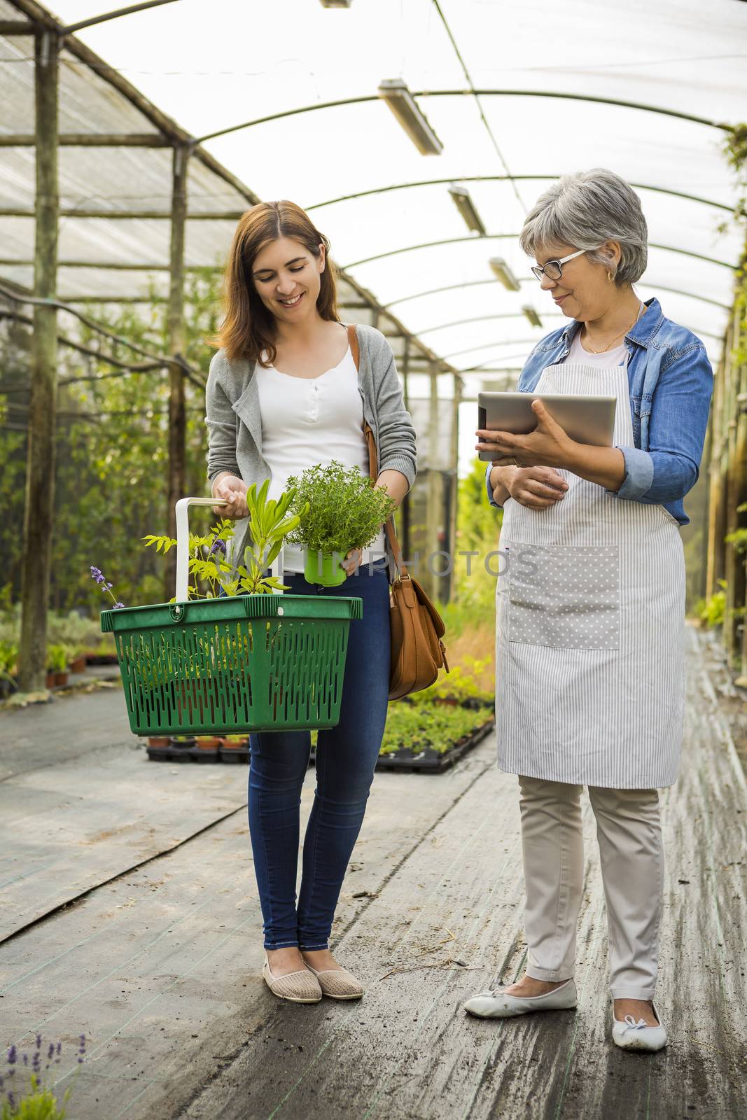 Beautiful mature florist helping a female customer to choose plants