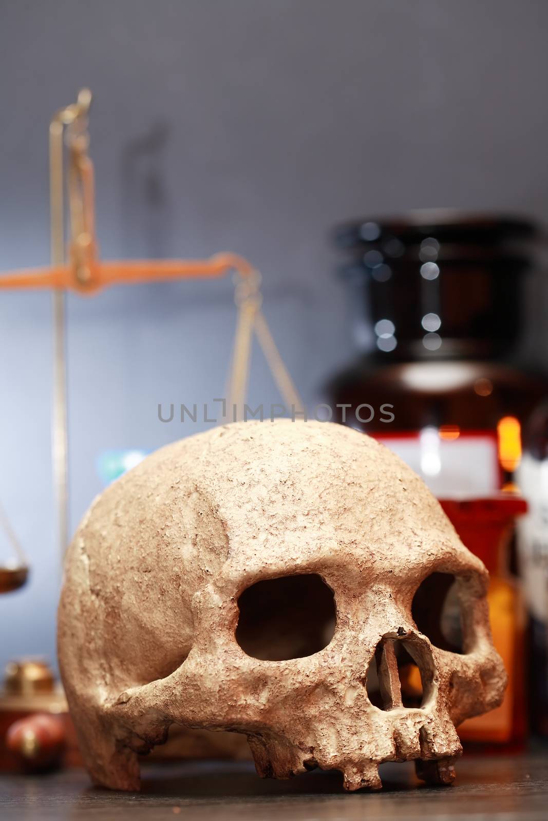 Medical laboratory. Human skull on blurred background with weight scale and flasks