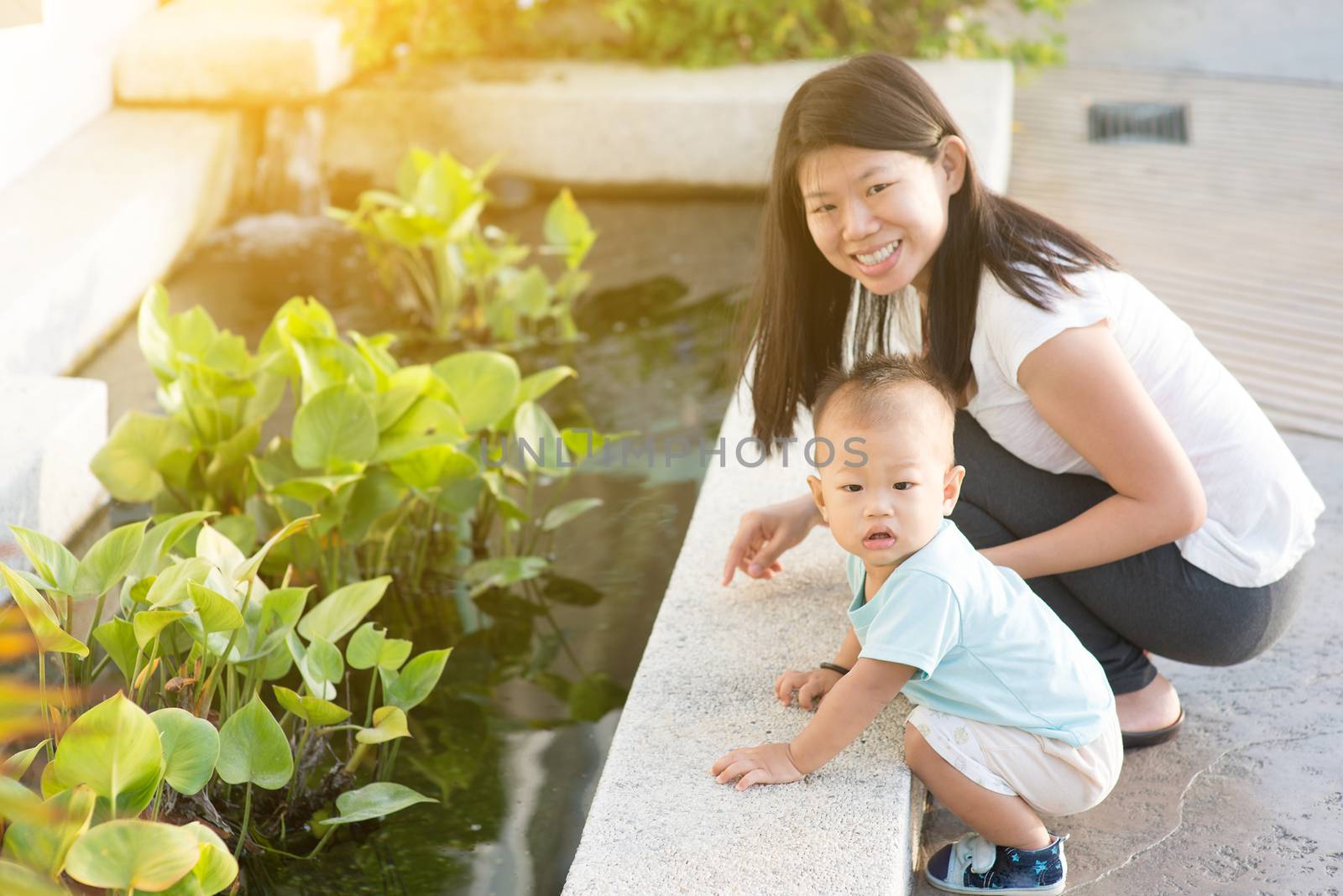Asian mother and child having fun time at outdoor in sunset during vacations.