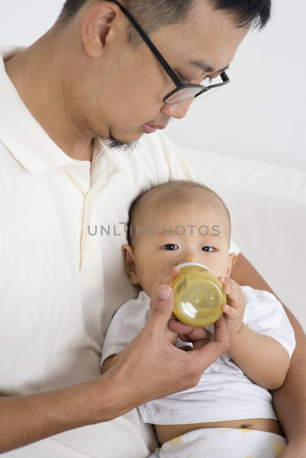 Father bottle feed solid food fruit puree to baby, Asian family lifestyle at home.