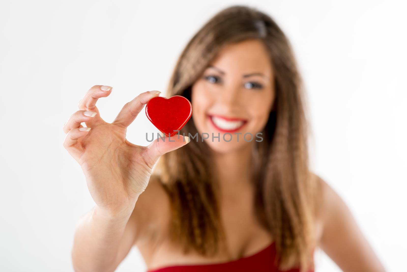 Beautiful smiling girl holding a red heart. Selective focus. Focus on the heart.