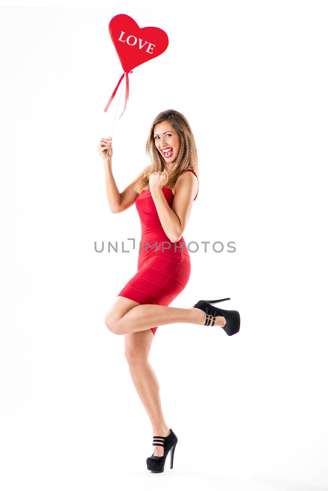 Beautiful cheerful girl standing and holding red heart. Looking at camera.