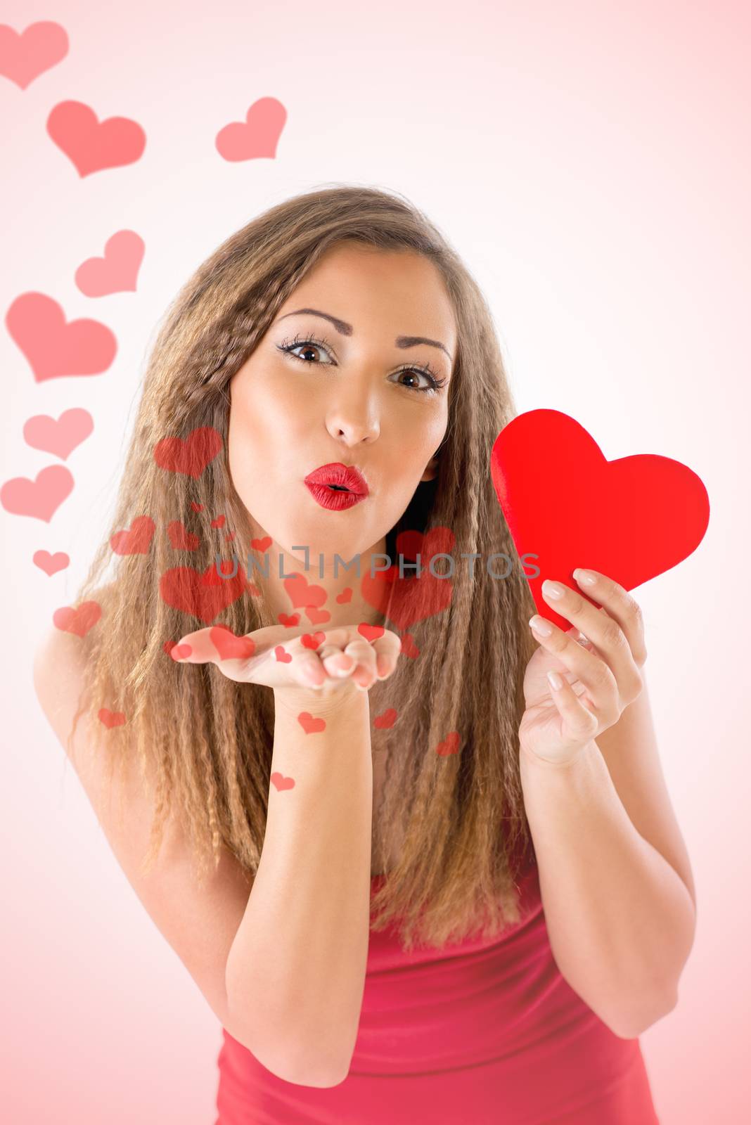 Beautiful smiling girl holding red heart. She is sending a kiss with many flying heart. Looking at camera.