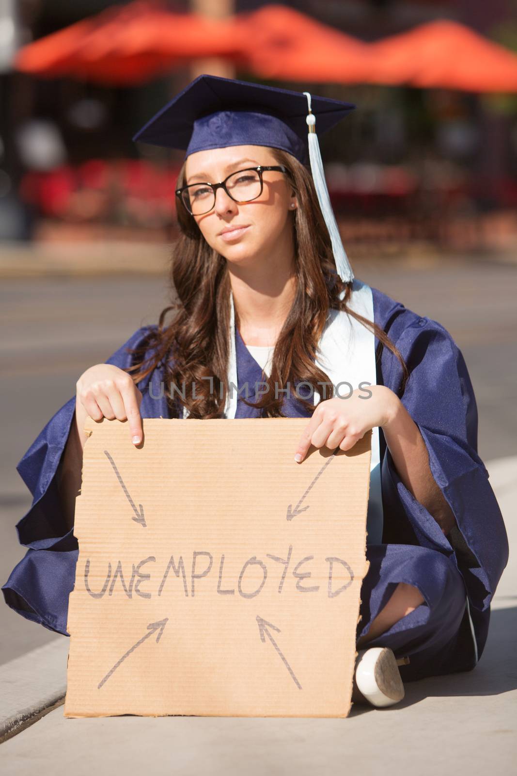 Single unemployed young female graduate sitting with sign