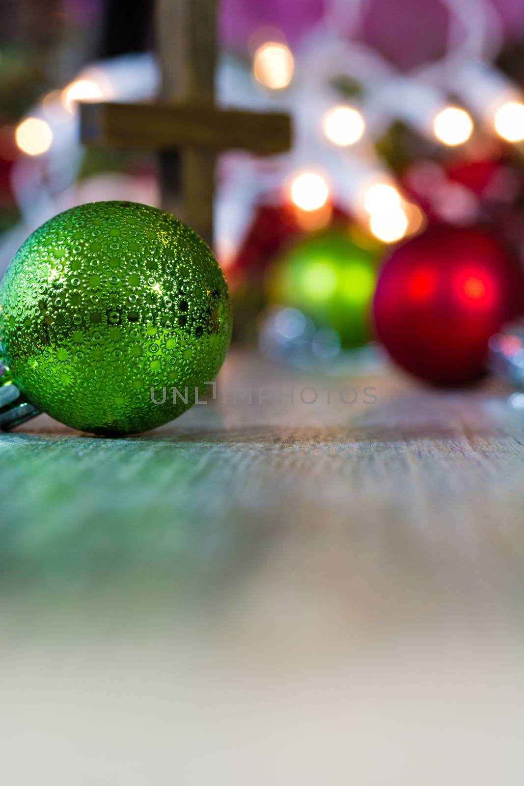 Colorful Christmas ornaments and lights on a wooden background with a christian cross.