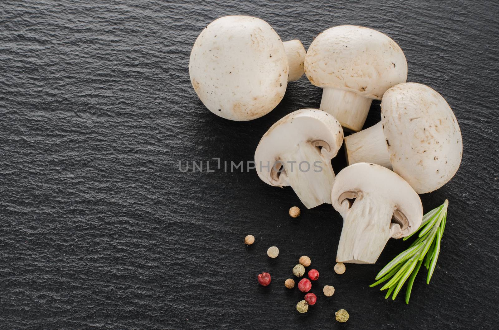 Fresh mushrooms with spices and herbs on a black board.