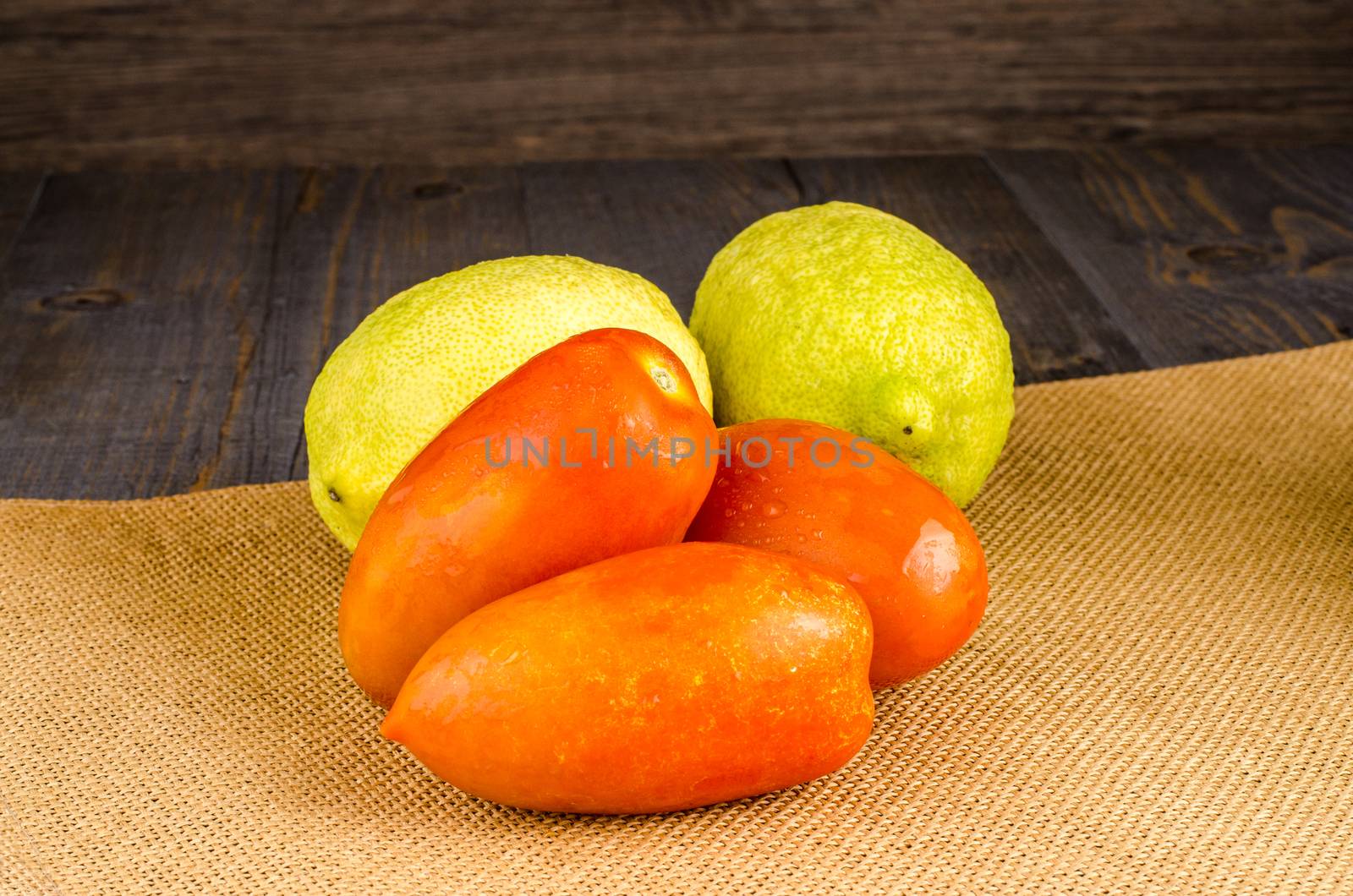 Assortment of fresh tomatoes and lemons on brown background