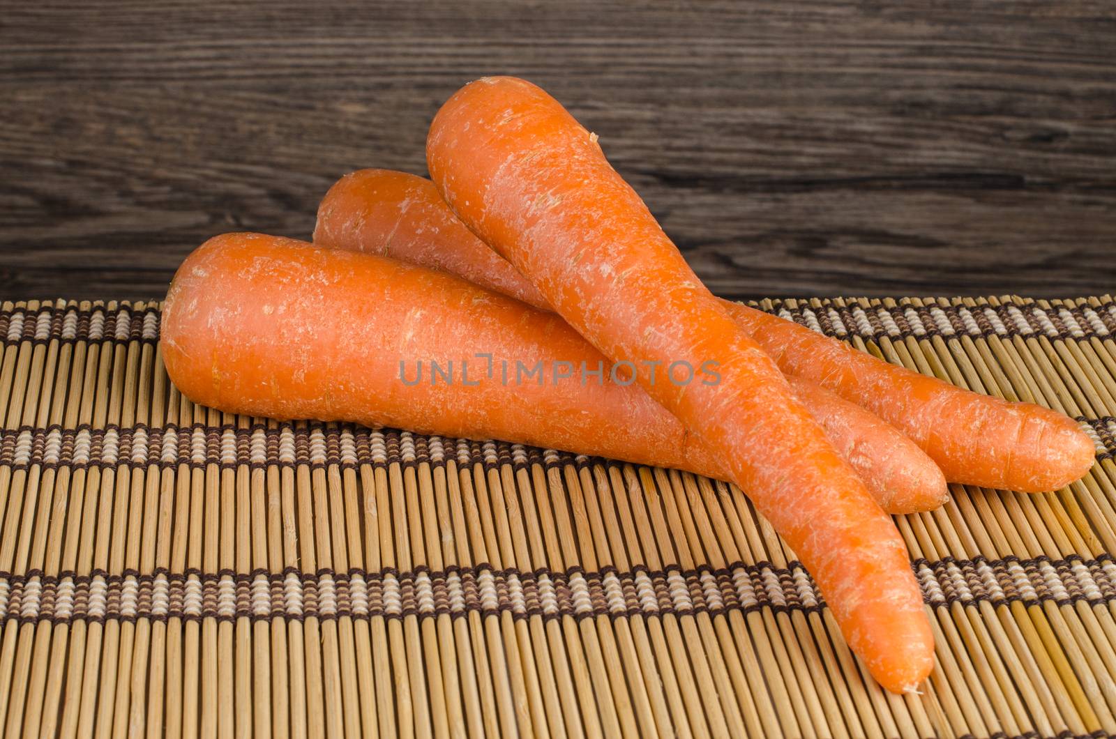 Fresh carrot on straw palcemat and wood background