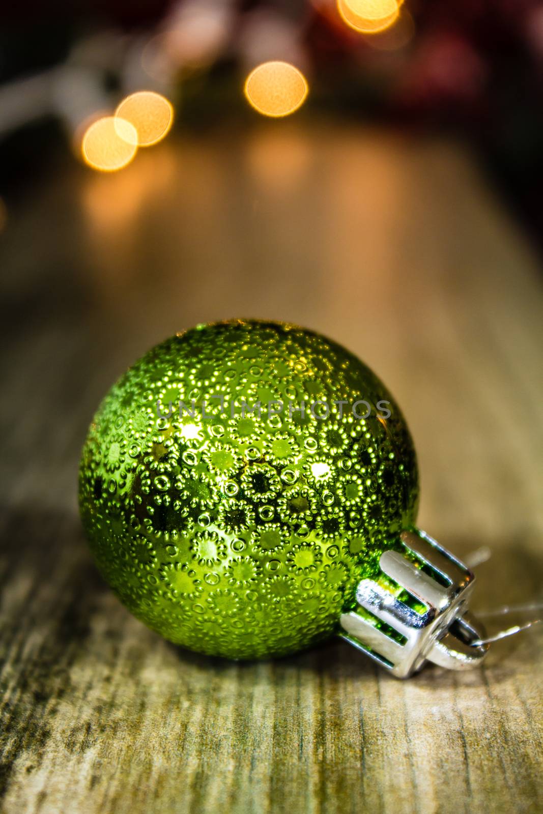 A green patterned Christmas ornament on a wooden background.