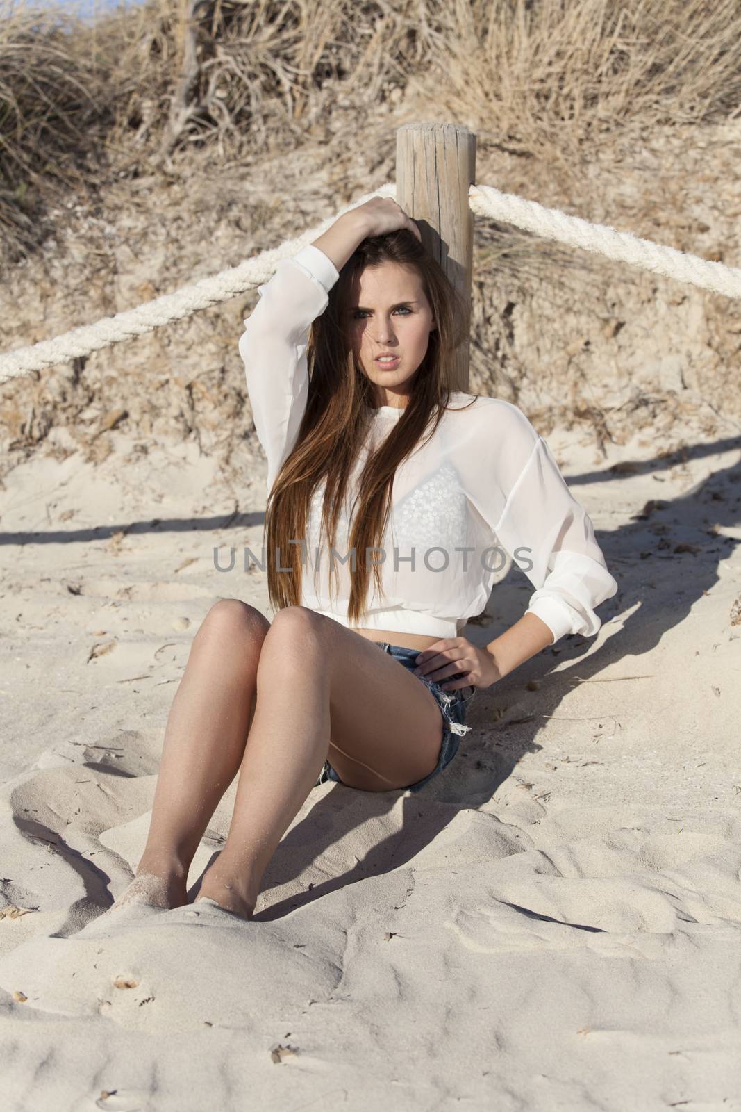 woman sitting on a beach by bernjuer