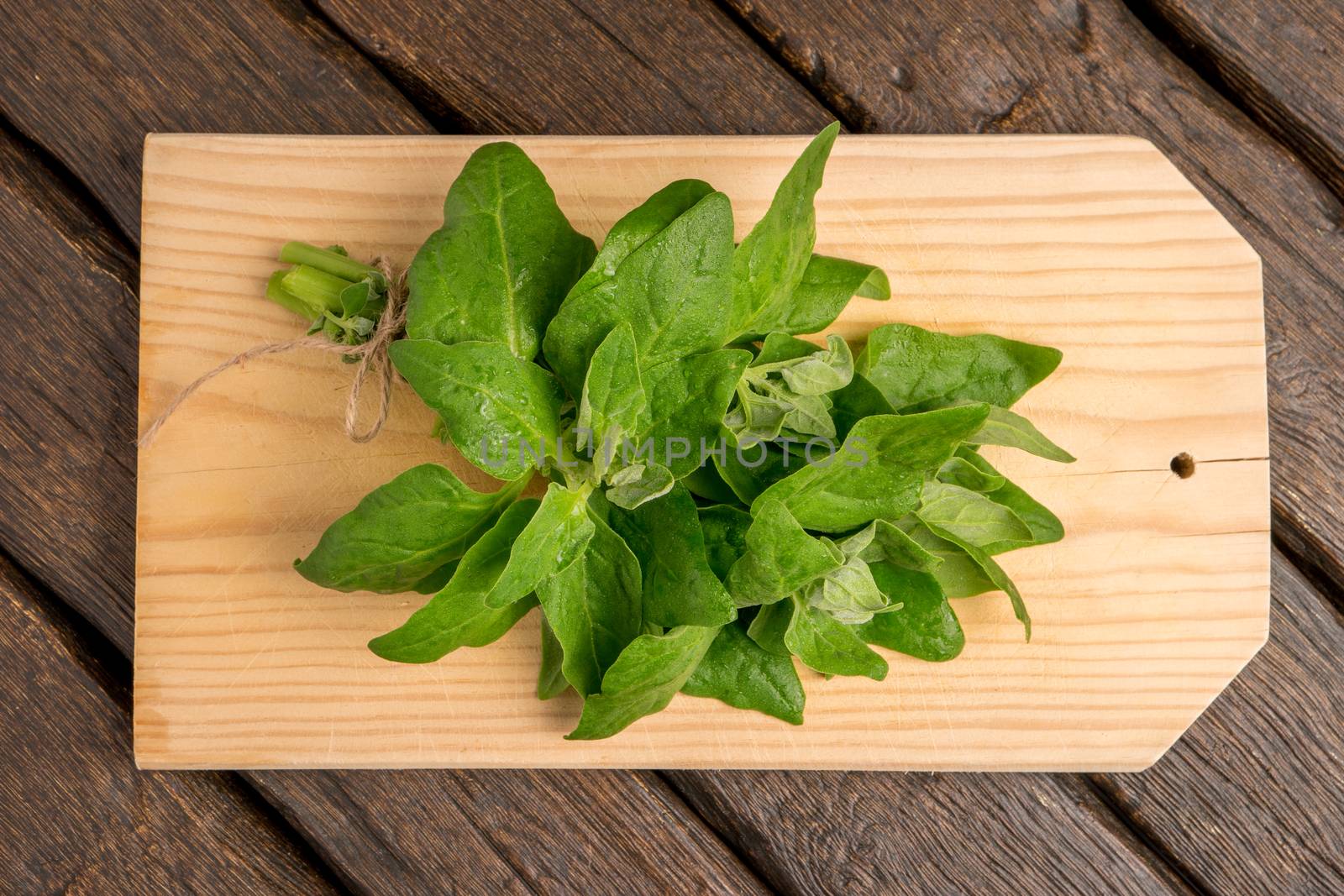 Spring spinach leaves on cutting board and dark wooden background