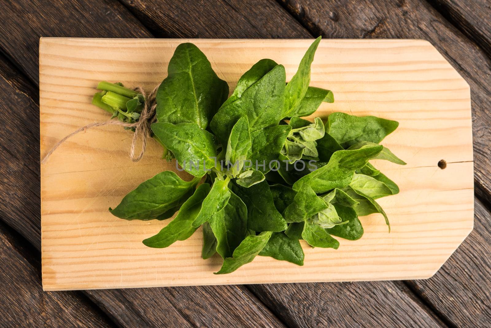 Spring spinach leaves on cutting board and dark wooden background