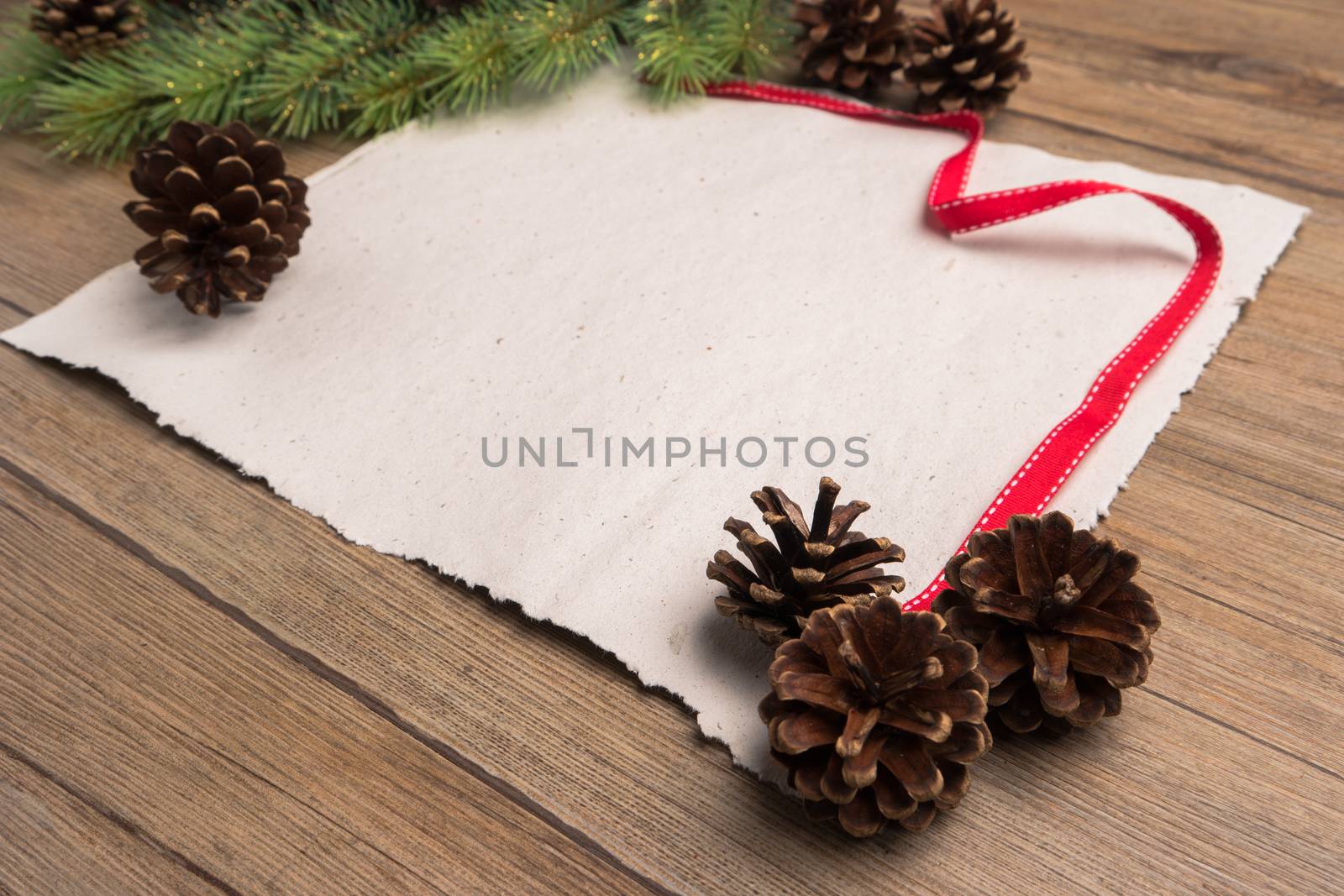 Christmas border design with pine cone, fir branches and ribbon on parchment paper over old oak wood