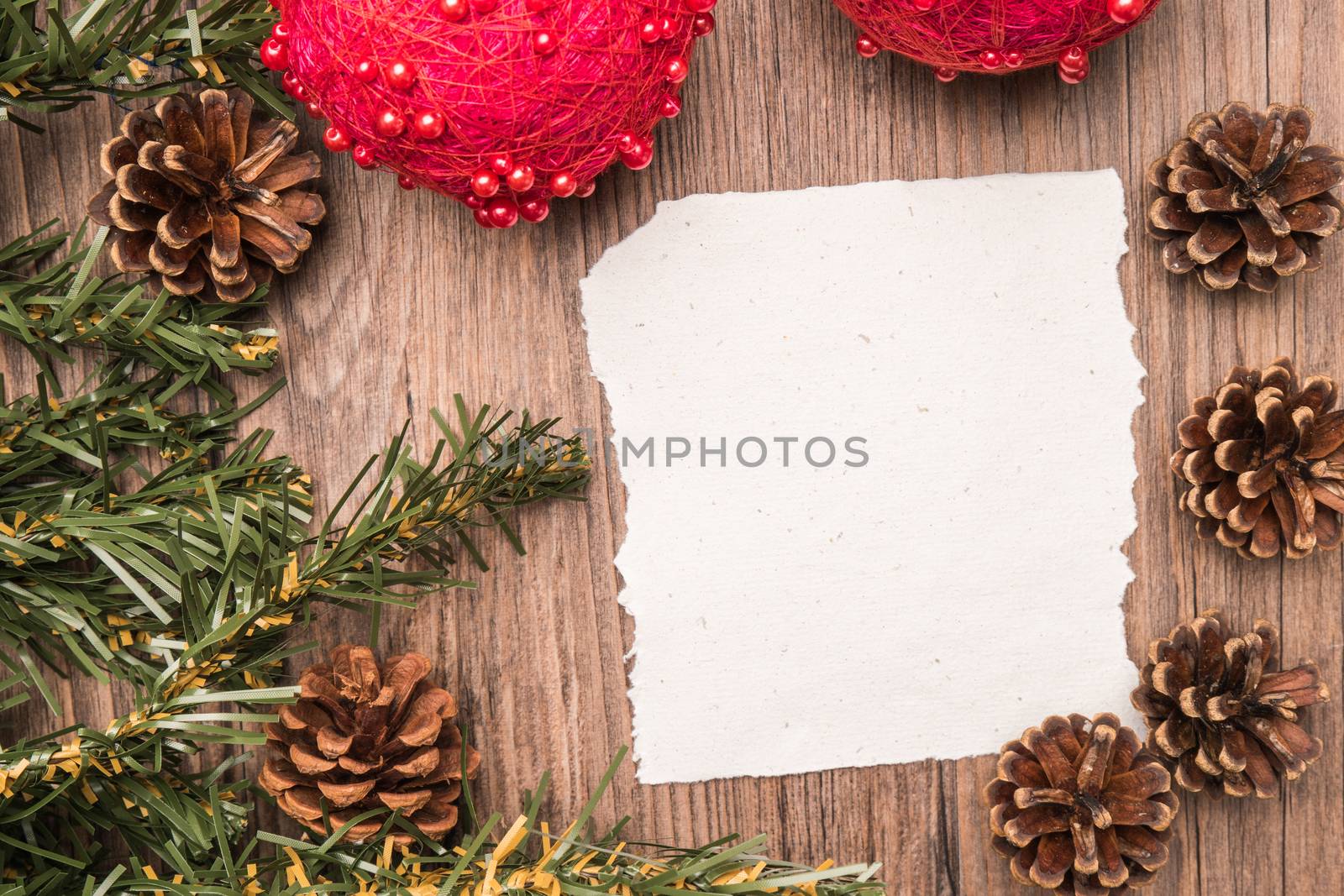 Christmas border design with pine cone, fir branches and christmas balls on parchment paper over old oak wood