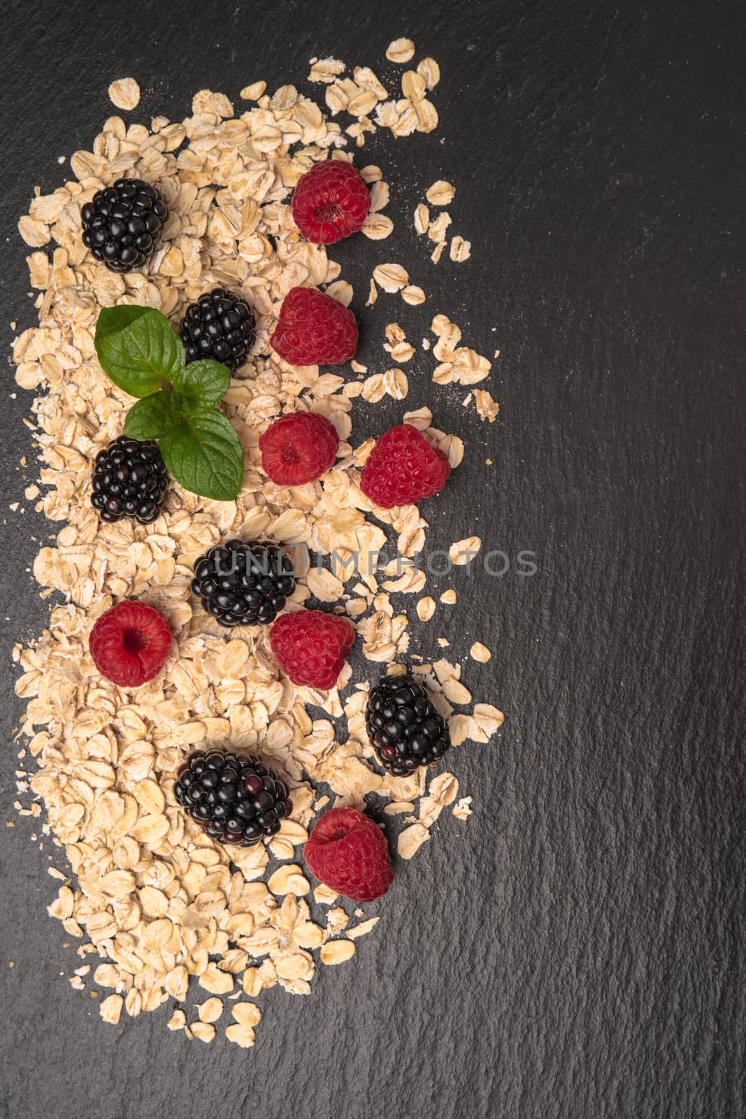 Healthy breakfast. Fresh granola, oatmeal with blackberries and raspberries on a black slate background. copy space