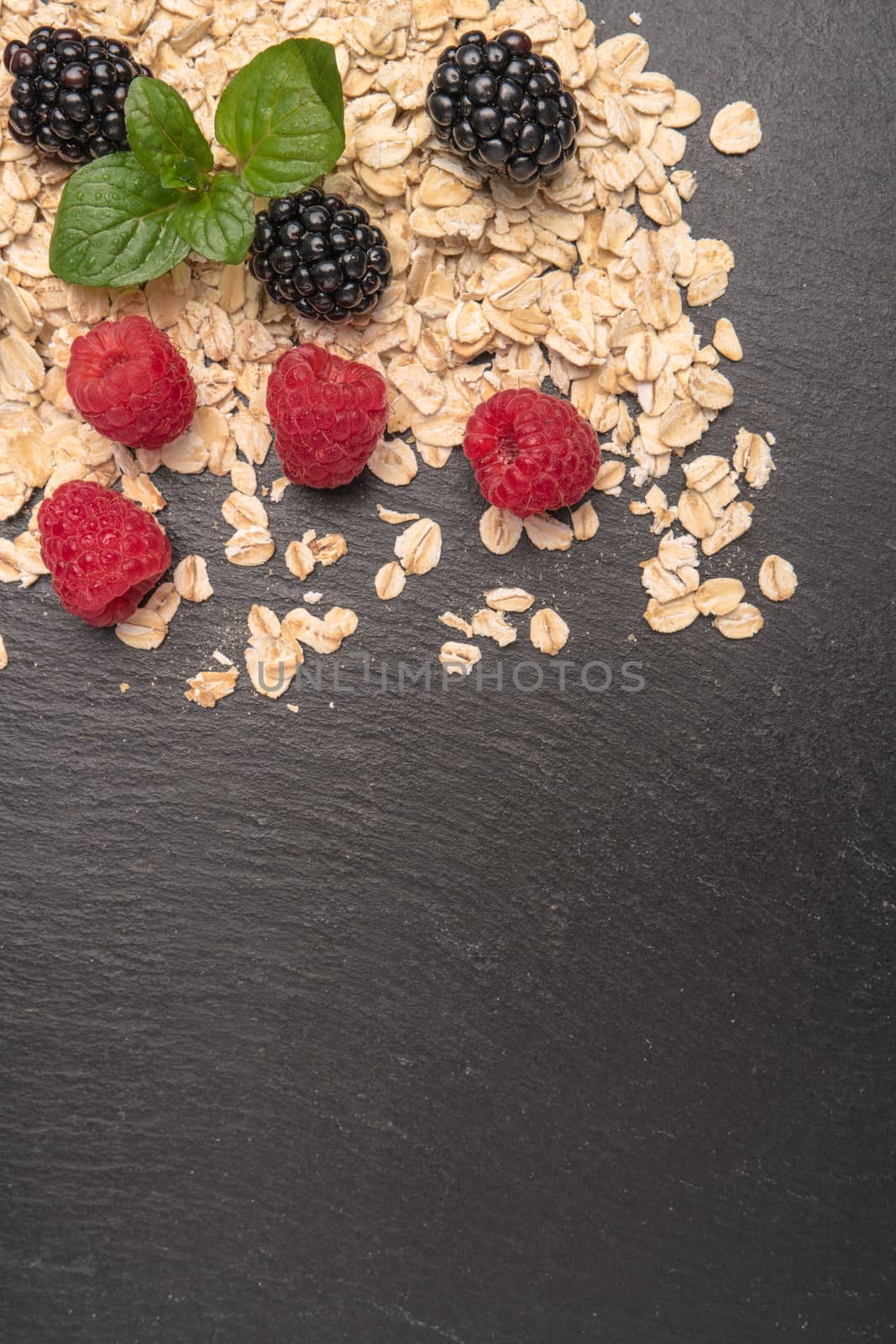 Healthy breakfast. Fresh granola, oatmeal with blackberries and raspberries on a black slate background. copy space