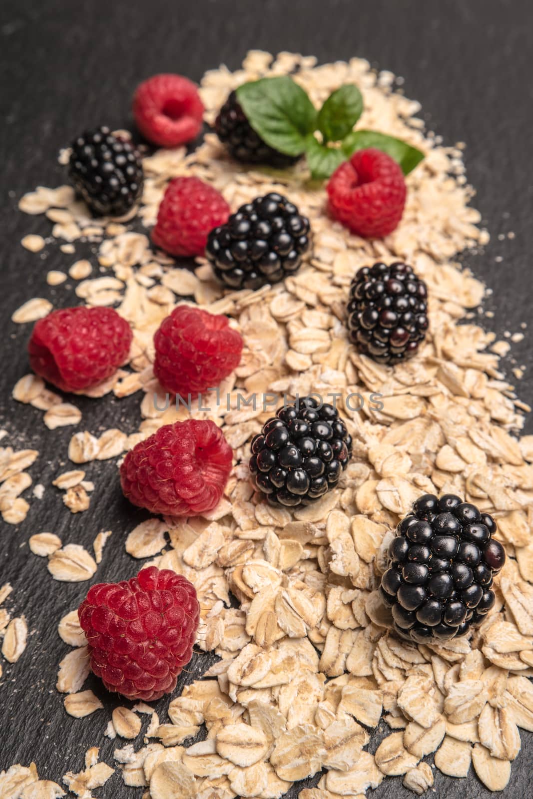 Healthy breakfast. Fresh granola, oatmeal with blackberries and raspberries on a black slate background. copy space