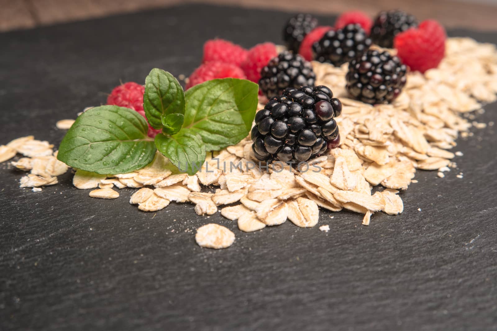 Healthy breakfast and berries on slate background, close-up by AnaMarques