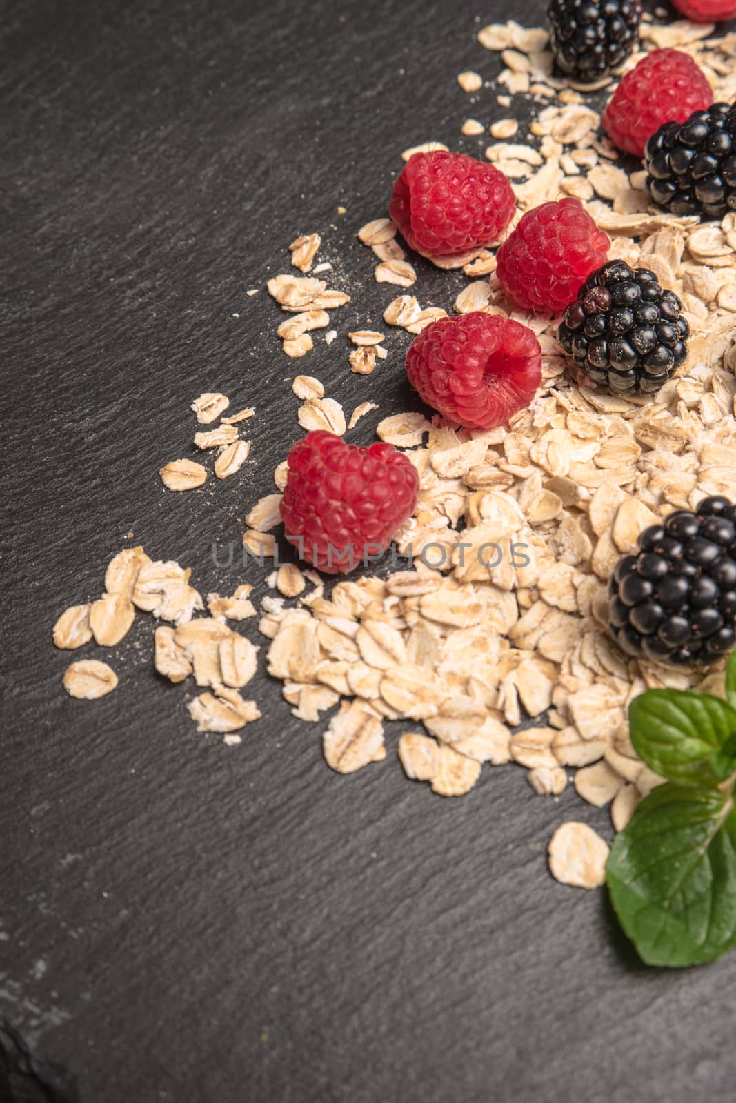 Healthy breakfast. Fresh granola, oatmeal with blackberries and raspberries on a black slate background. copy space