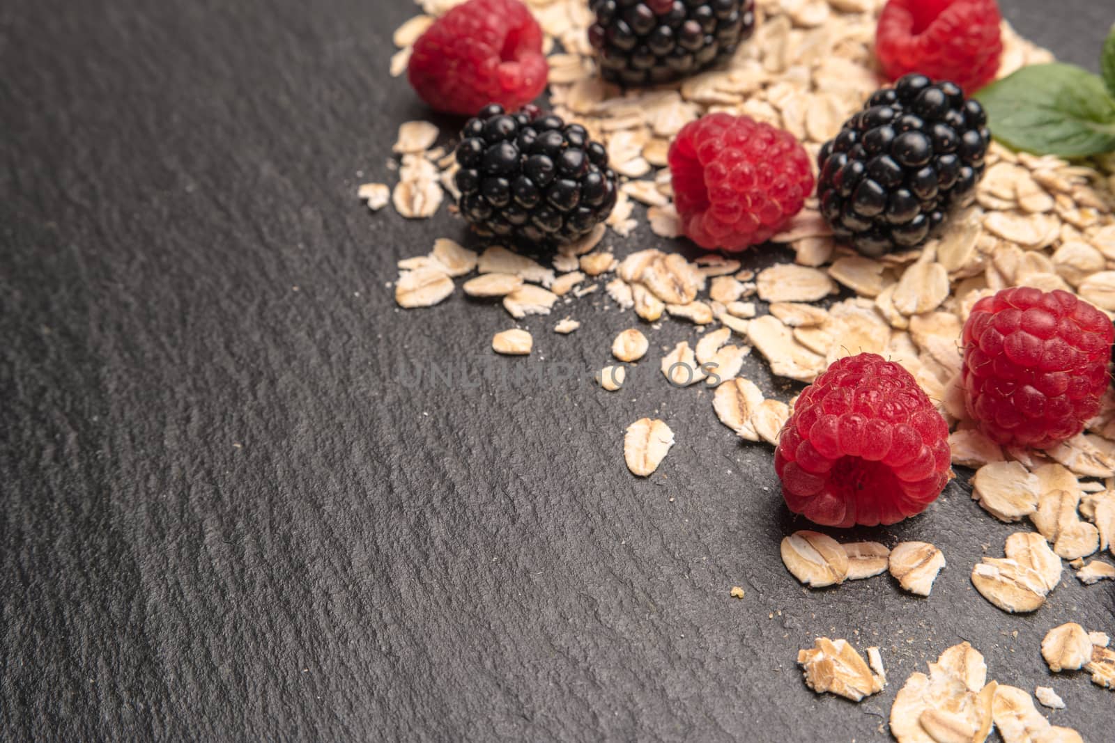 Healthy breakfast and berries on slate background, close-up by AnaMarques