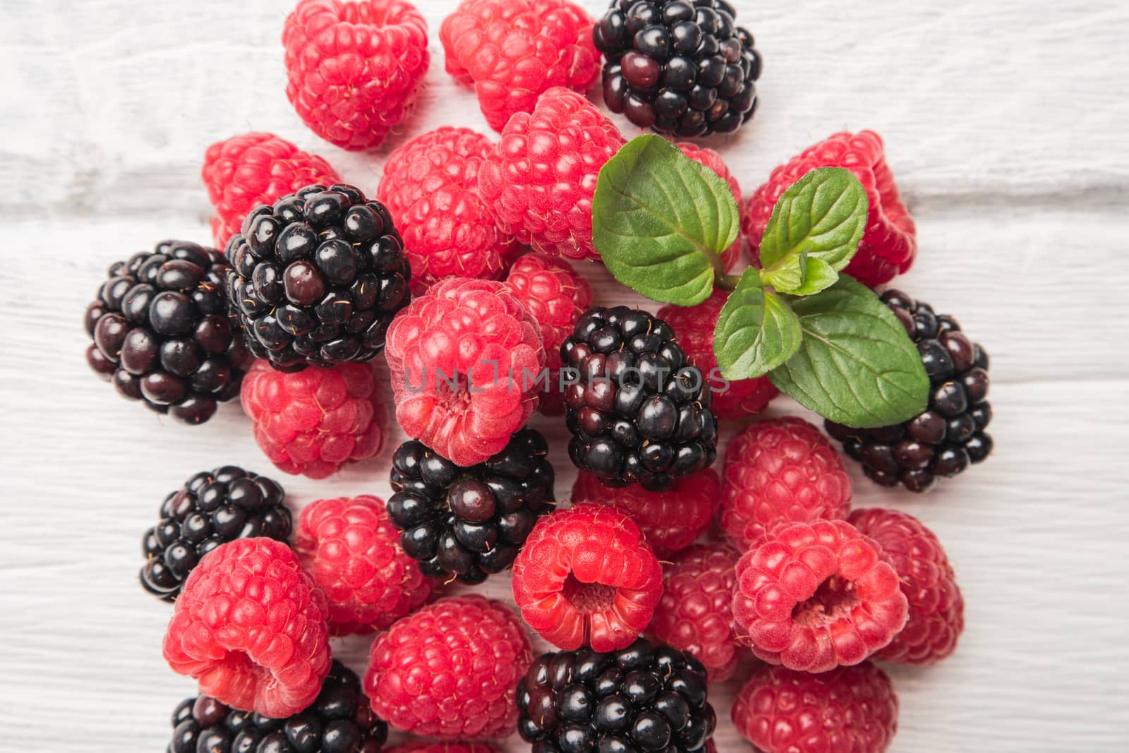 Ripe sweet raspberries and blackberries on wood table background