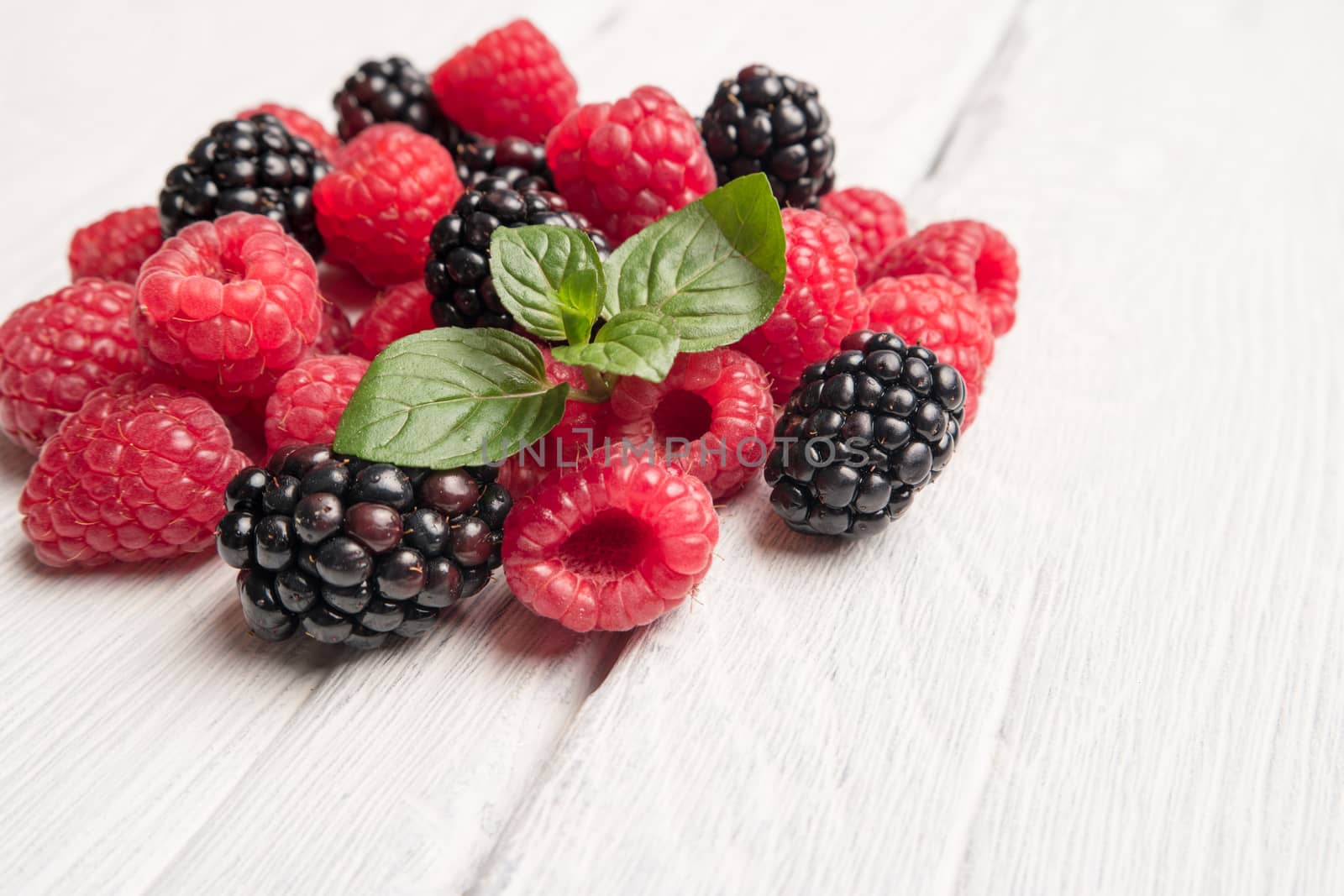 Ripe sweet raspberries and blackberries on wood table background