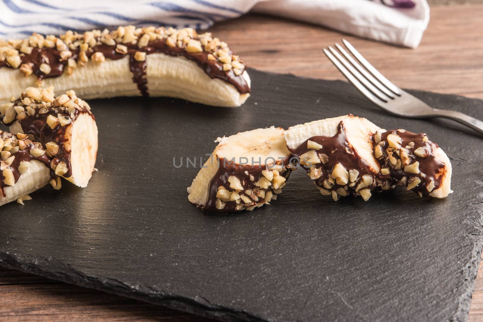 Fresh banana with melted chocolate and nuts coverage by AnaMarques